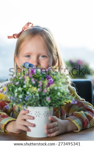 Portrait of a cute little hipster looking girl with flowers and bow over the window background