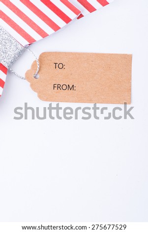 Red gift bow with stripes and cardboard tag over the white background, isolated