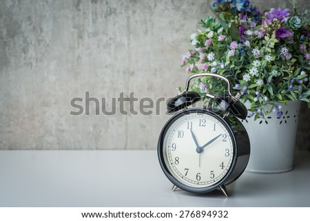 Vintage alarm clock on a night table with flowers