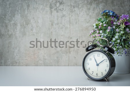 Vintage alarm clock on a night table with flowers