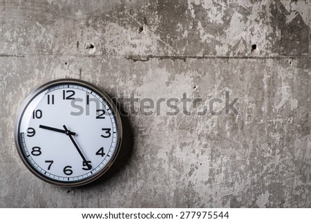 Dramatic picture of round wall clock hanging on the grey concrete wall
