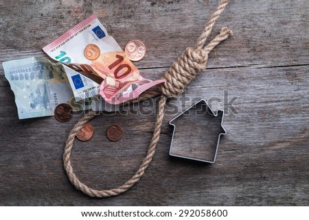 Hangman\'s noose with house, keys and money on brown wooden background