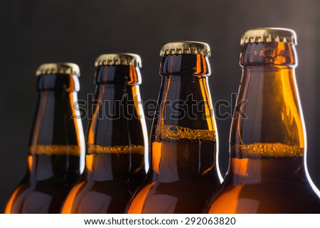 Ice cold beer bottles in a row over the grey concrete wall background