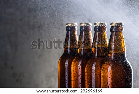 Ice cold beer bottles with drops of dew over the grey background