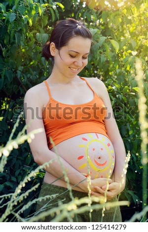 Beautiful pregnant woman portrait with drawing on the abdomen.