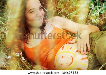 Happy pregnant woman portrait with drawing of smile on the abdomen.