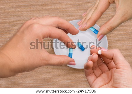 Hands taking pills from a plate