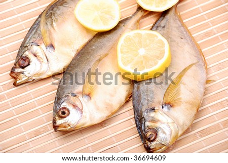 Smoked fish with a lemon on a bamboo