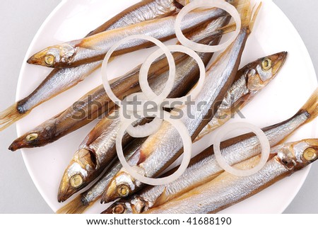 Smoked fish with rings of onions on a plate