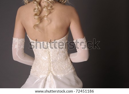 Back of bride in wedding dress on a gray background.