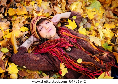Smiling happy girl portrait, lying in autumn leaves. Outdoor.