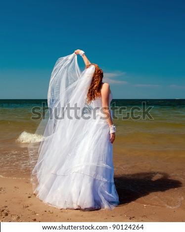Bride in the wind. Pretty lady in a wedding dress on sea.