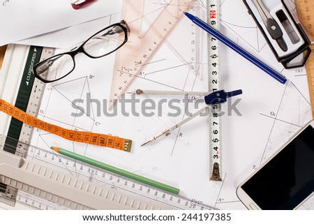 messy architect desk with paper, ruler, compasses and mobile phone