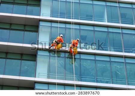 Ho Chi Minh City, Vietnam - March 09, 2015 : two workers were cleaning the mirror of an office building