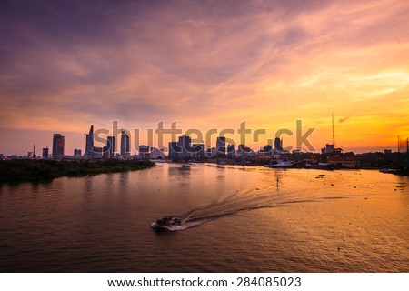 Ho Chi Minh\'s Panorama view over the Saigon River. Dramatic lighting spectacular sunset is highlighted by a canoe surfing on the water at a faster rate