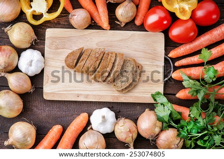 Bread on the wooden cutting board with vegetables