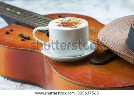 Cappuccino coffee cup, guitar and hat
