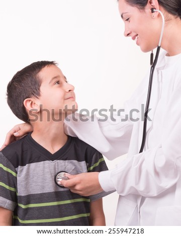 woman doctor dressed in white hugging and auscultating a child with stethoscope looking at each other
