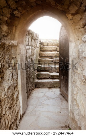 Massive stone wall with open door and rays of light behind