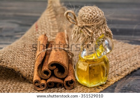 Essential cinnamon oil in bottle and cinnamon sticks on sackcloth