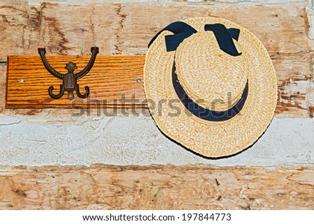 Wall with a hanger and ladies hat hanging on it.