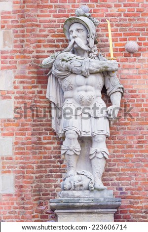 Statue of the knight with golden sword and foot on the head. The statue is in front of the house in Gdansk, Poland.