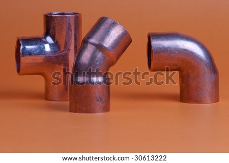 Close up of three metal pipe fittings tee, bend, and corner