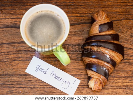 Coffee with croissant on the wooden background with good morning note