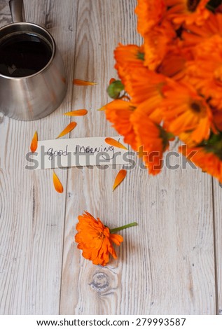 Orange flowers with coffee and good morning note