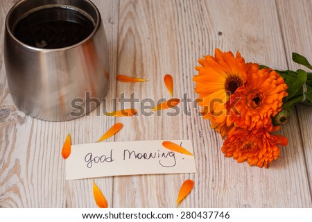 Orange flowers, coffee and good morning note on a white wooden background