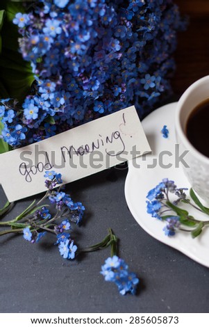 Bunch of blue flowers (forget-me-nots) and coffee with good morning note