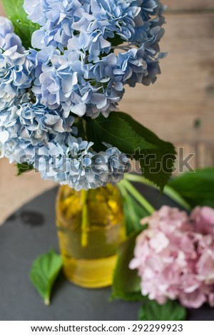Blue and pink hydrangea in a vase on a stone and wooden background