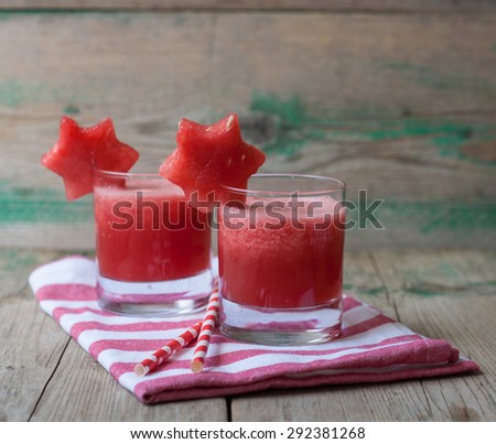 Watermelon smoothie on a red striped napkin and two straws on a wooden background