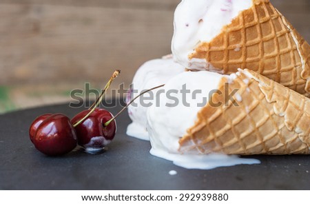 Cherry ice cream in cones with cherry on the top on a dark background