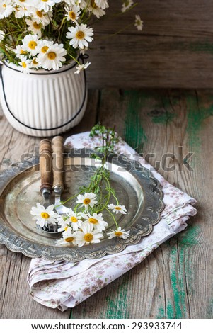 Silver plate with fork and spoon and fresh flowers on the napkin and wooden background