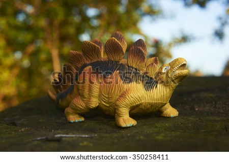Toy dinosaur figurine in a real nature scenery outdoors.
