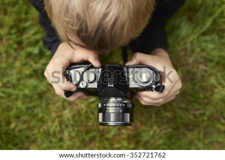 Child blond boy with Vintage photo film camera photographing outside