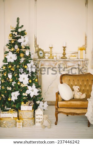New Year\'s and Christmas interior in gold color with a chimney portal, a fir-tree and gifts