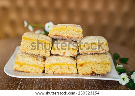 cakes on a white plate which costs on a table, lie flowers nearby