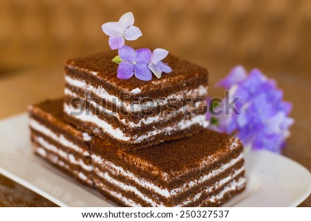 chocolate cakes on a white plate which costs on a table, lie flowers nearby