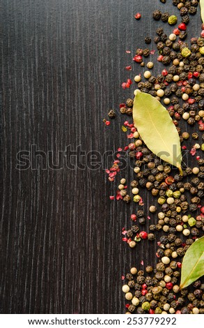 laurel leaves on a mix four pepper on black wooden table