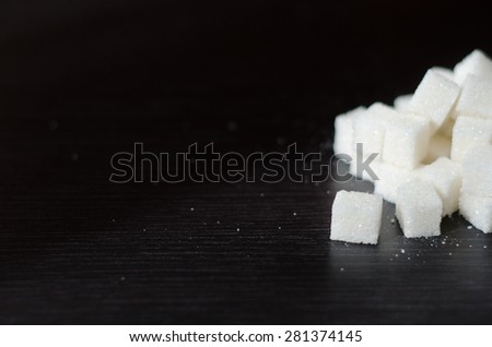 White sugar cubes piled in a heap on the black desk