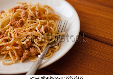 Spaghetti with sauce on a white plate with a fork