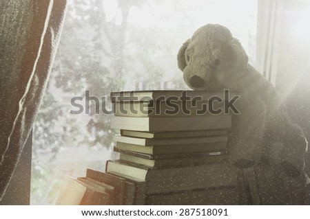 Soft vintage background for children. Childhood memory: Teddy dog sitting on books. Books stacked on the windowsill