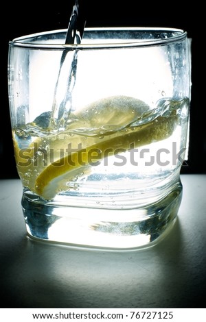 Back lit glass of water with lemon in it