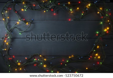Glowing Christmas tree garland in the form of a frame on a blue wooden background