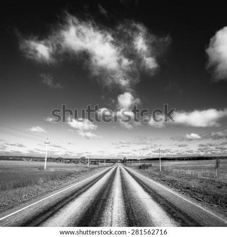 Empty road disappearing into the distance, sky with clouds. Black and white photography