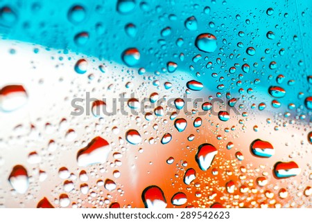 rain drops on the front windshield of a car. orange background
