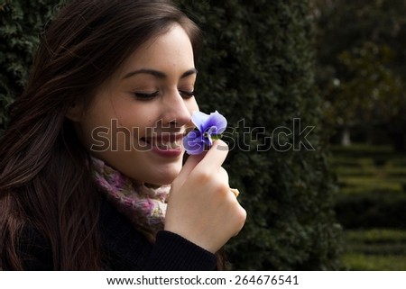 Girl smelling a flower in a park.