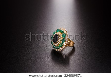 yellow gold diamond ring with emeralds and sapphire isolated on black background